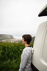 Attractive young female located next to her campervan while enjoying morning fresh air