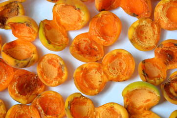 Semi-dried fresh apricots lie on paper and dry in the sun.