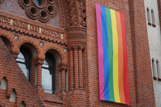 Gro&szlig;e Regenbogenfahne an der Fassade einer Kirche in Berlin
