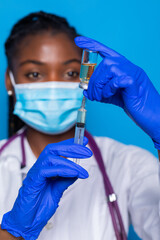 medicine, vaccination and healthcare concept - african american female doctor or scientist in mask with syringe