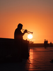 Silhouette of a lone Trumpeter playing his Trumpet at Sunset in a Public Area