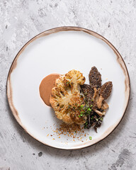 Cauliflower steak with morels on plate, restaurant dish, copy space