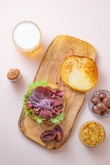 Hamburger with sliced pastrami served with lettuce on a freshly baked sesame bun over white background