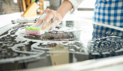 Woman is cleaning black induction stove.