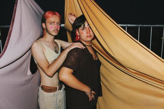 Artistic portrait of queer young nonbinary couple & friends with full face makeup and septum piercing in flash at night outdoors balcony shoot *2