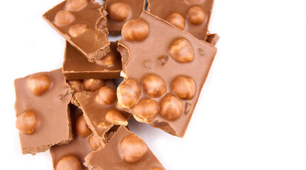 Macro photo of Chocolate bar. Broken pieces over white background. Pieces of milk chocolate with nuts isolated on white background