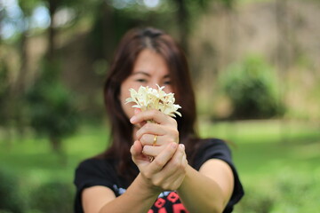 woman holding white good smell flowers in the park.