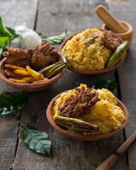 Cooked food ingredients dal khichdi, fried potatoes, onion rings on earthen plates with use of selective focus