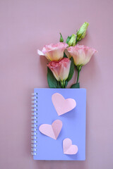Purple notebook cover and cut out heart mockups on pink background. Symbol of love and Valentine's day. Flat lay, top view, copy space
