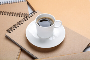 Cup of coffee and notebooks on table, closeup