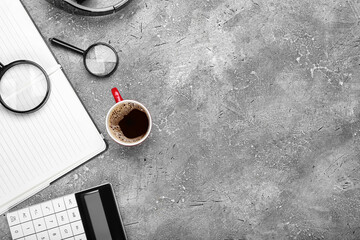 Cup of coffee, magnifiers, calculator and notebook on grunge background
