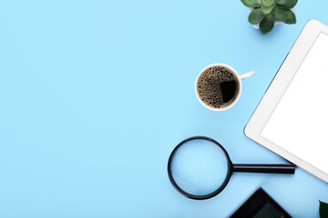 Cup of coffee, tablet computer and magnifier on color background