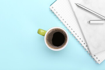 Cup of coffee, notebooks and pen on color background
