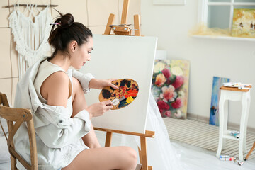 Obraz premium Young female artist painting in workshop