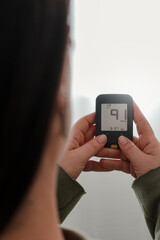 close-up shot from the back of a Latina woman using a glucometer