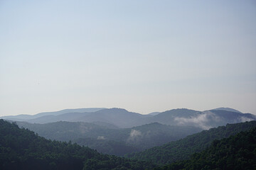Fog rolls through the picturesque forest mountains.