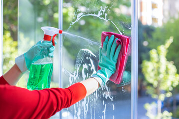 Woman hand in rubber protective glove with microfiber rag wiping