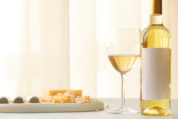 Bottle and glass of wine with snacks on table