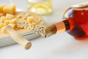 Bottle of wine with corkscrew on table, closeup - obrazy, fototapety, plakaty