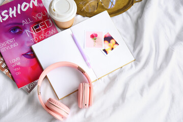 Modern headphones with notebook on bed