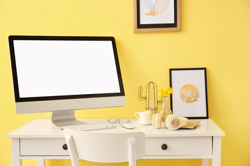 Modern workplace with computer near color wall