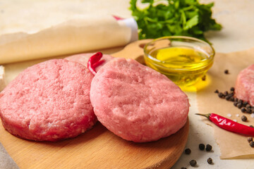 Wooden board with raw cutlets made of fresh forcemeat on table, closeup