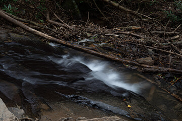 Water flows through a creek, long exposure.