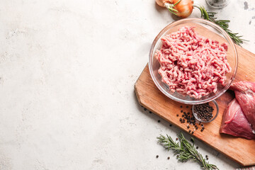 Bowl with fresh forcemeat and ingredients on light background