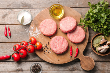 Composition with raw cutlets made of fresh forcemeat on wooden background