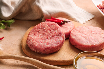 Wooden board with raw cutlets made of fresh forcemeat on table, closeup