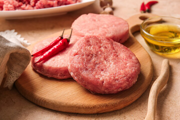 Wooden board with raw cutlets made of fresh forcemeat on table, closeup