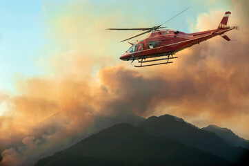 Fototapeta na wymiar Firefighters helicopter monitor the fire in the mountain