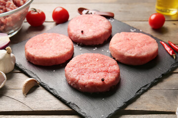 Board with raw cutlets made of fresh forcemeat on wooden background