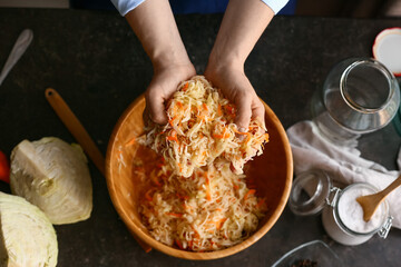 Woman preparing tasty sauerkraut at kitchen table, closeup