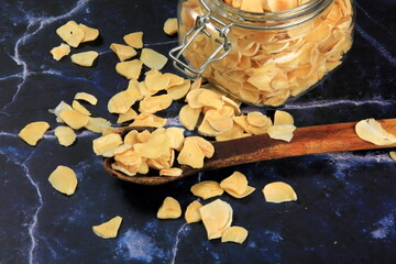 Dried garlic flakes on dark blue marble background. Dried vegetables
