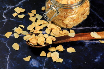 Dried garlic flakes on dark blue marble background. Dried vegetables