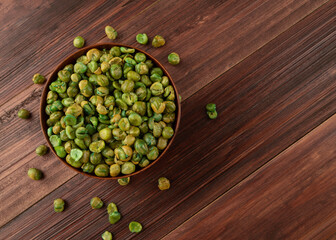 Top view of Salted green peas in wooden bowl on the table, Flat lay, Healthy snack, Vegetarian food.