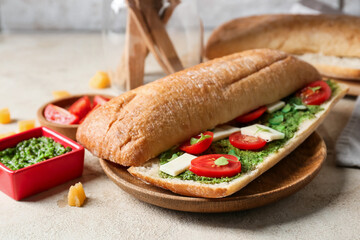 Tasty sandwich with pesto sauce on table