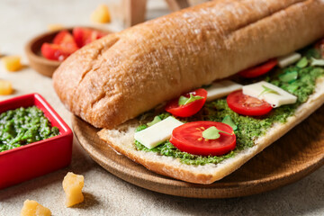 Tasty sandwich with pesto sauce on light background, closeup