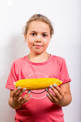 Girl with boiled sweet corn. Summer meals for children. Sweet boiled corn in hands of child.