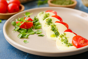 Plate with caprese salad and pesto sauce on color background, closeup