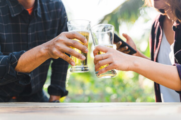 Cropped shot of people holding beer glasses celebrating in the summer camping party outdoor. Friends clinking bottle of beer during camping outdoor