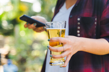 Cropped shot of people holding beer glasses celebrating in the summer camping party outdoor. Friends clinking bottle of beer during camping outdoor