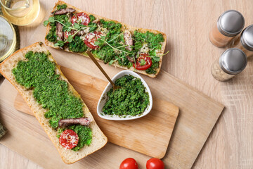 Preparing of tasty sandwich with pesto sauce on wooden background