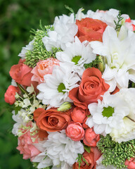 Round wedding bridal bouquet of orange and white flowers on green background, selective focus, close-up
