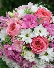 Round wedding bridal bouquet of pink and white flowers on green background, selective focus, close-up