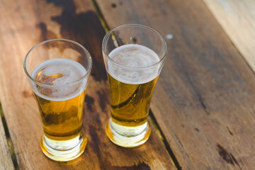 Cropped shot of people holding beer glasses celebrating in the summer camping party outdoor. Friends clinking bottle of beer during camping outdoor