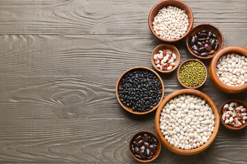 Bowls with different legumes on dark wooden background