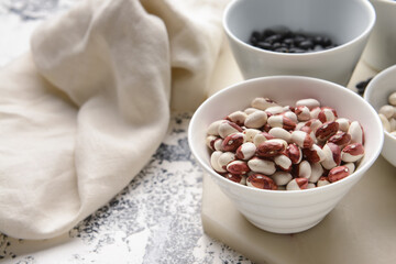 Bowls with different types of beans on grunge background