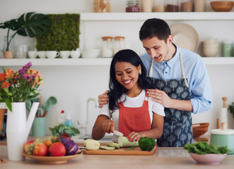 happy multiracial couple cutting vegetables and cooking on the kitchen